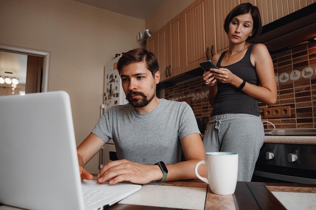 Paar liest in der Küche Nachrichten und benutzt Laptop