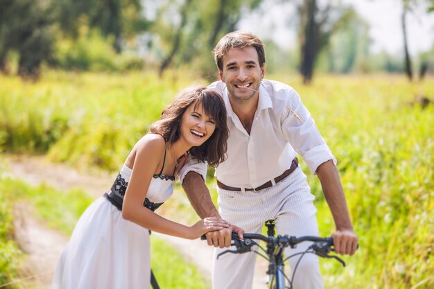 Paar Mann und Frau im Hochzeitsstil mit Fahrrädern in der Natur glücklich