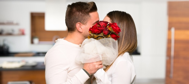 Paar mit Blumen und Küssen in einem Haus