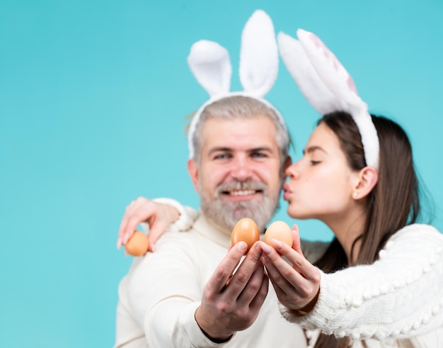 Paar mit Eiern für Ostern Glückliches Paar mit Hasenohren und Eiern auf blauem Hintergrund, isoliertes Häschen