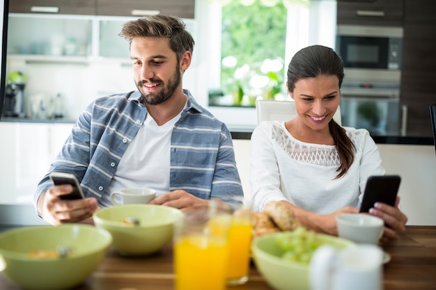 Paar mit Handy beim Frühstück