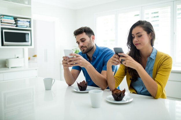 Paar mit Handy in der Küche zu Hause