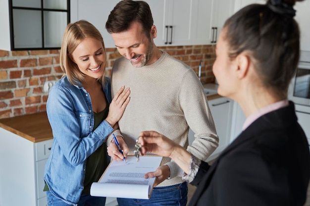 Paar mit Immobilienmakler unterschreibt Vertrag für neue Wohnung