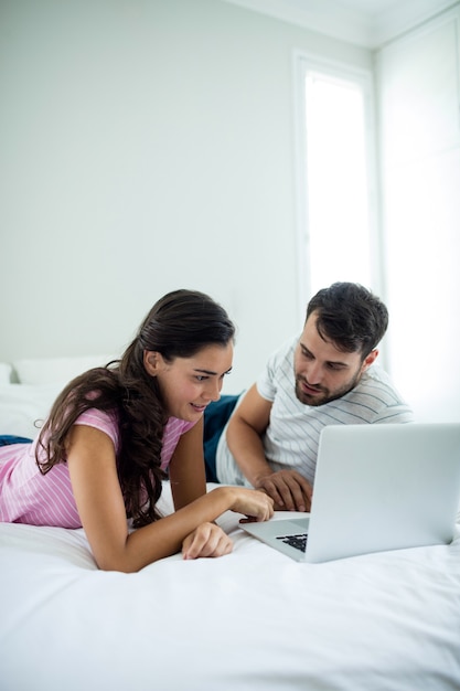 Paar mit Laptop im Schlafzimmer zu Hause