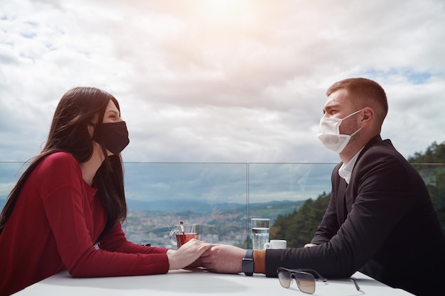 Paar mit medizinischer Schutzmaske bei Kaffeepause in einem Restaurant, neues normales Coronavirus-Konzept