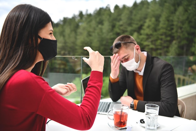 Paar mit medizinischer Schutzmaske bei Kaffeepause in einem Restaurant, neues normales Coronavirus-Konzept
