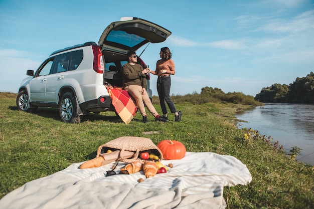 Paar mit Picknick-Date am warmen Herbsttag am Flussstrand Kopienraum