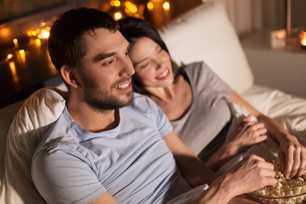 Paar mit Popcorn, das nachts zu Hause fernsieht