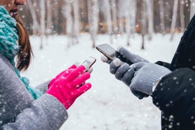 Paar mit Smartphone im Winter mit Handschuhen für Touchscreens