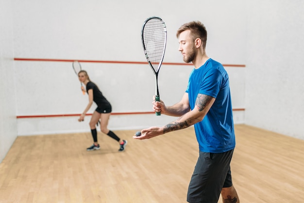 Paar mit Squashschlägern, Indoor-Trainingsclub