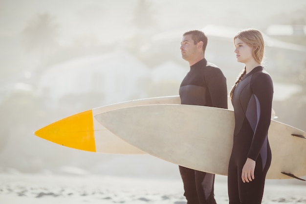 Paar mit Surfbrett stehen am Strand