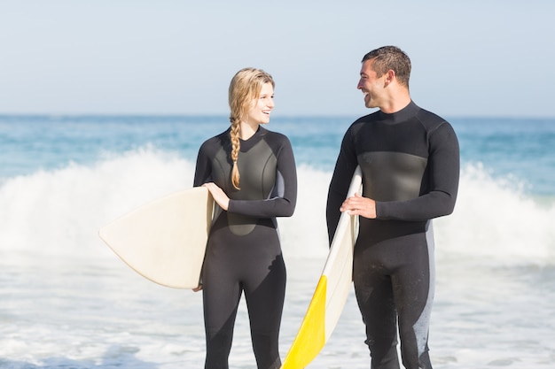 Paar mit Surfbrett zu Fuß am Strand