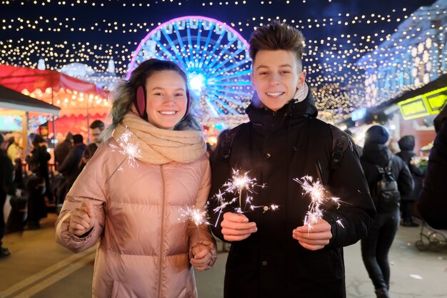 Paar mit Wunderkerzen feiern und Spaß auf dem Weihnachtsmarkt haben