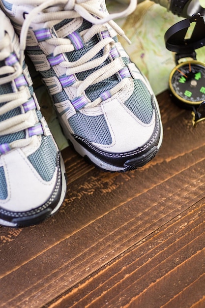 Paar neue Damen-Wanderschuhe mit Topo-Karte auf Holzhintergrund.