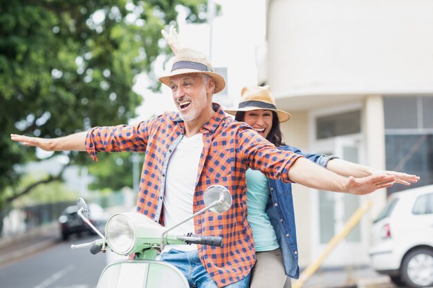 Paar Reiten Moped mit ausgestreckten Armen