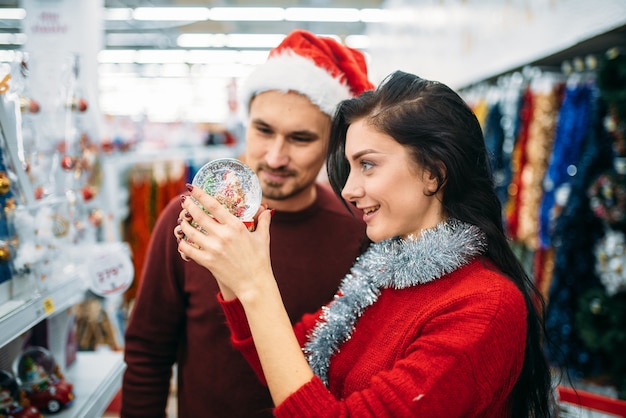 Paar schaut auf Schneekugel im Supermarkt