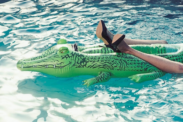 Paar schwarze Damenschuhe mit hohen Absätzen aus Krokodilleder im Schwimmbad