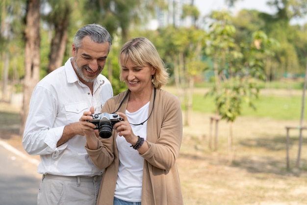 Paar Senioren im Ruhestand üben Fotografie und betrachten Kamerabilder zusammen im Park