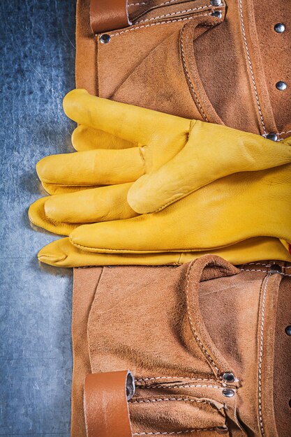 Paar Sicherheitsarbeitshandschuhe Werkzeuggürtel auf metallischem Hintergrund Konstruktionskonzept