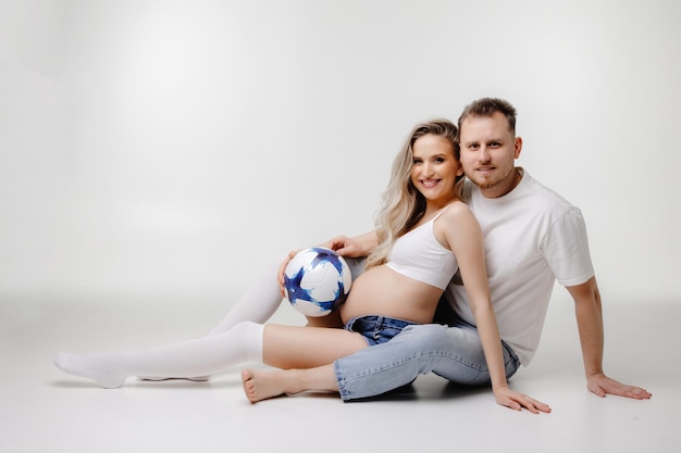 Paar sitzt auf dem Boden schwangere Frau mit ihrem Mann sitzt auf einem weißen Hintergrund