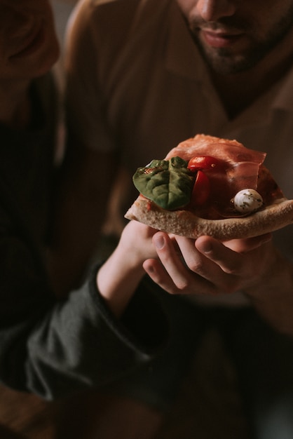 Paar sitzt auf dem Teppich und isst Pizza