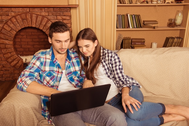 Paar sitzt auf einem Sofa mit Laptop