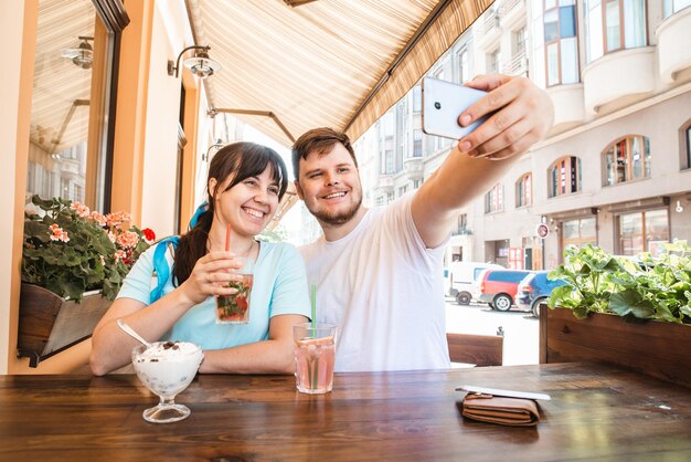 Paar sitzt im Café am Sommertag und nimmt Selfie-kühle Getränke