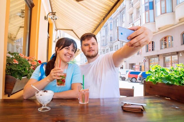 Paar sitzt im Café am Sommertag und nimmt Selfie-kühle Getränke