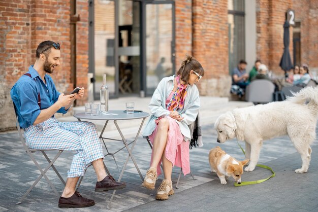 Paar sitzt im Café, während Hunde herumspielen