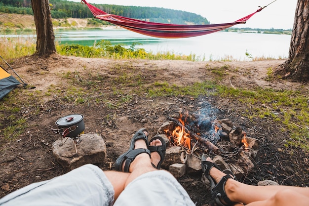 Foto paar sitzt in der nähe eines lagerfeuers mit einem wunderschönen blick auf den see