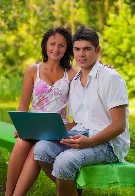 Paar sitzt mit Laptop im Park