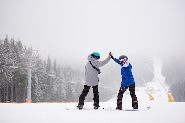 Paar Snowboarder mit High Five auf der Skipiste