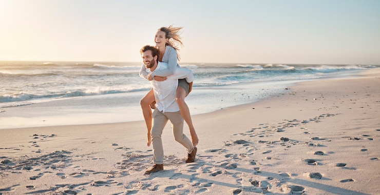 Foto paar spazieren gehen und piggyback am strand für reisen bindung und sonnenuntergang während des urlaubs zusammen mit lächeln mann frau und tragen im freien durch das meer für liebe beziehung und abenteuer im urlaub