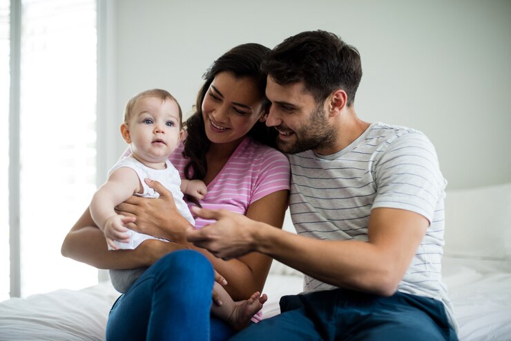 Foto paar spielt mit ihrem baby auf dem bett zu hause
