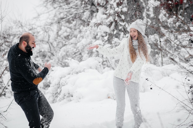 Paar spielt mit Schnee im Wald