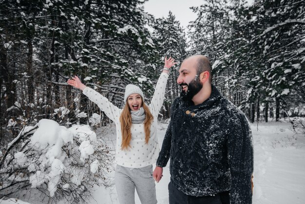Paar spielt mit Schnee im Wald