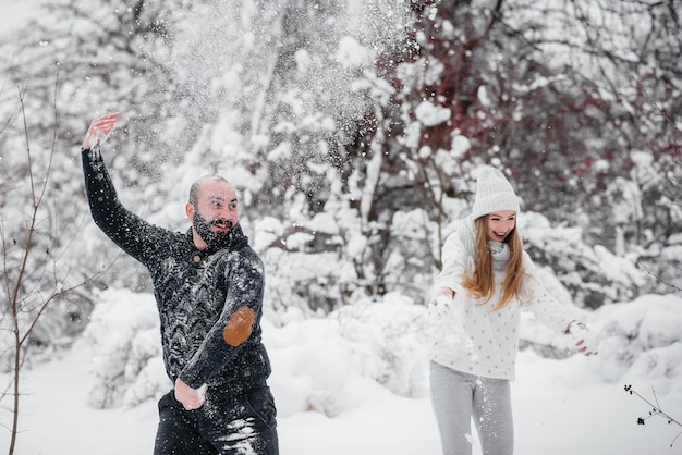 Paar spielt mit Schnee im Wald