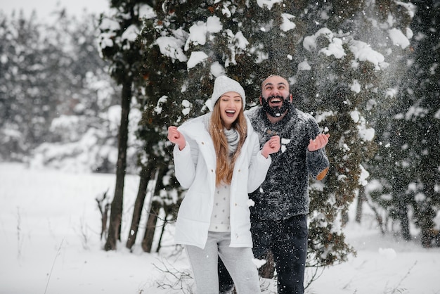 Paar spielt mit Schnee im Wald