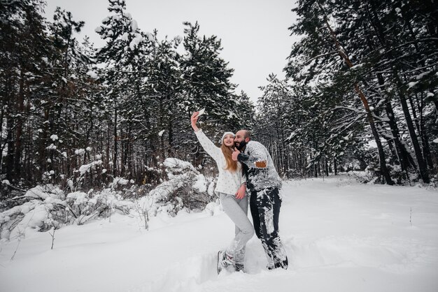 Paar spielt mit Schnee im Wald.