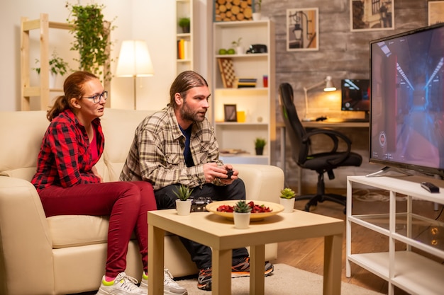 Paar spielt spät in der Nacht Videospiele auf einem Großbildfernseher im Wohnzimmer.