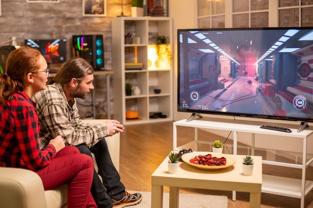 Paar spielt spät in der Nacht Videospiele auf einem Großbildfernseher im Wohnzimmer.