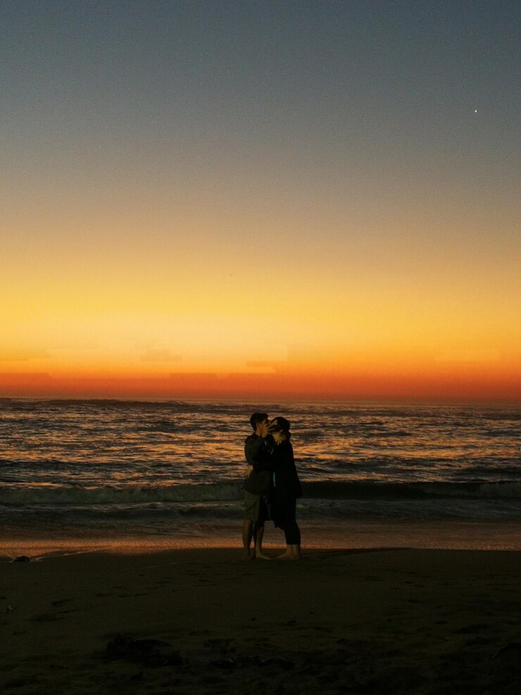 Foto paar steht am strand gegen den himmel bei sonnenuntergang