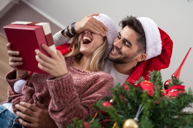 Paar tauscht Geschenke am Weihnachtsbaum aus