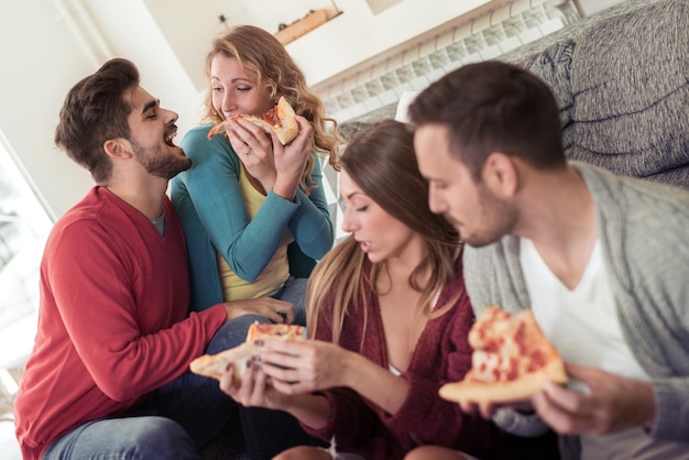 Paar teilt Pizza und isst zusammen im Wohnzimmer.