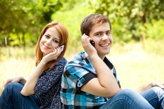 Paar telefoniert per Handy im Freien im Sommer.