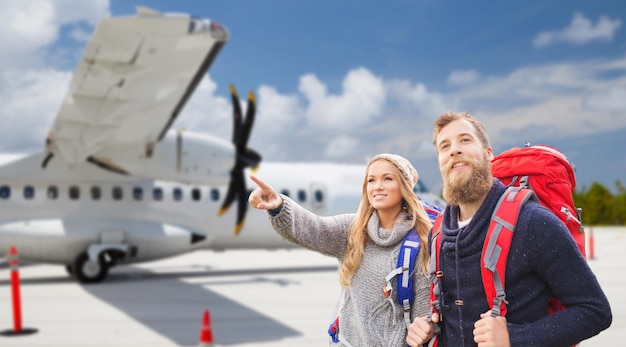 Foto paar touristen mit rucksäcken über dem flugzeug