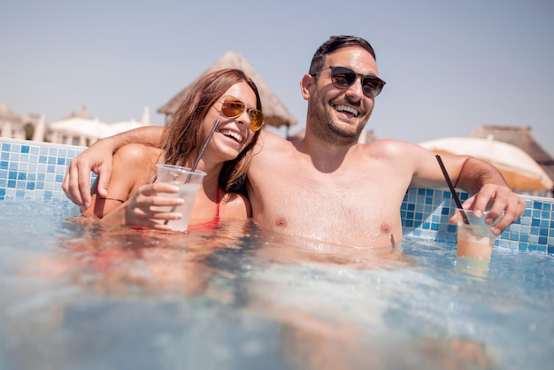 Paar trinkt einen Cocktail im Swimmingpool und entspannt sich