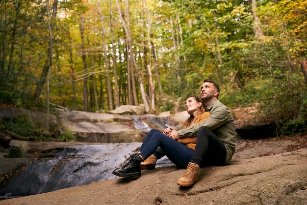 Paar umarmend sitzen am Fluss im Wald