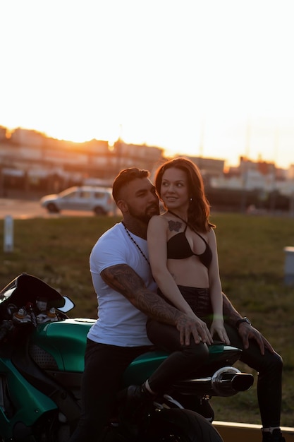 Foto paar umarmt sich bei sonnenuntergang in der nähe des motorrads