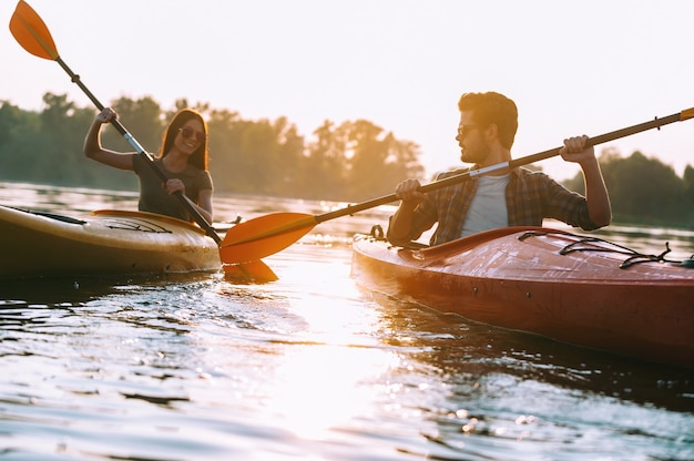 Paar zusammen Kajak fahren. Schönes junges Paar, das zusammen auf dem See Kajak fährt und lächelt